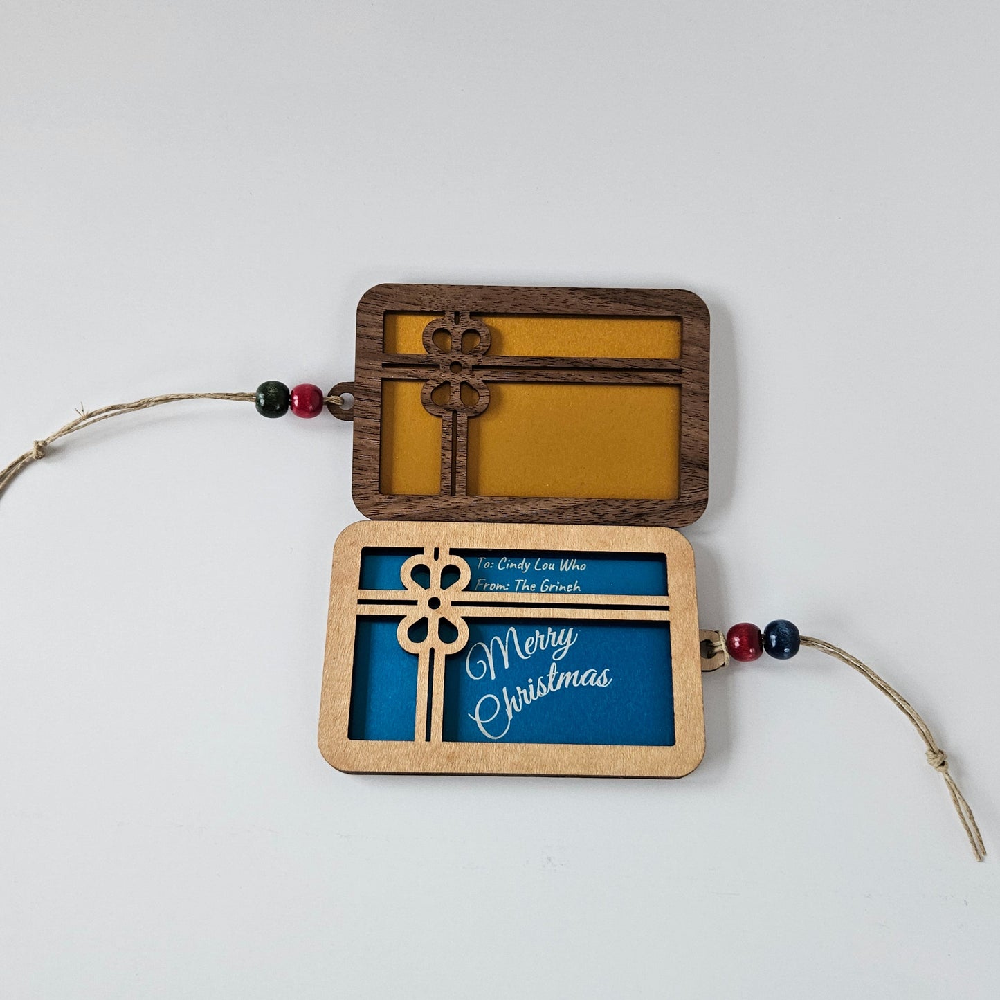 Decorative hanging gift card holder with wooden frame, metal card insert, and string on a white background