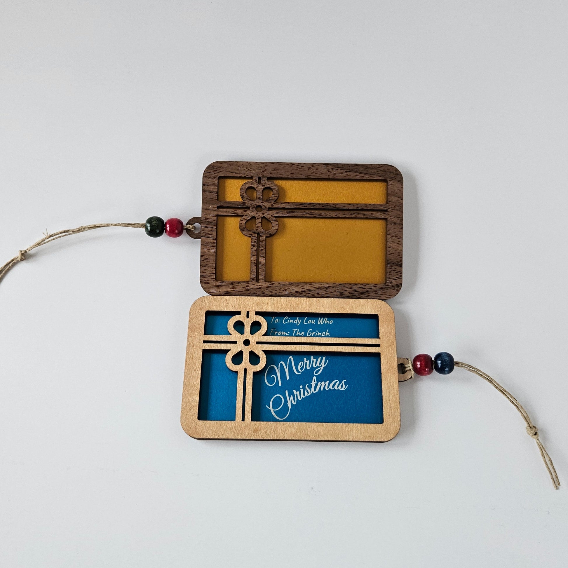 Decorative hanging gift card holder with wooden frame, metal card insert, and string on a white background