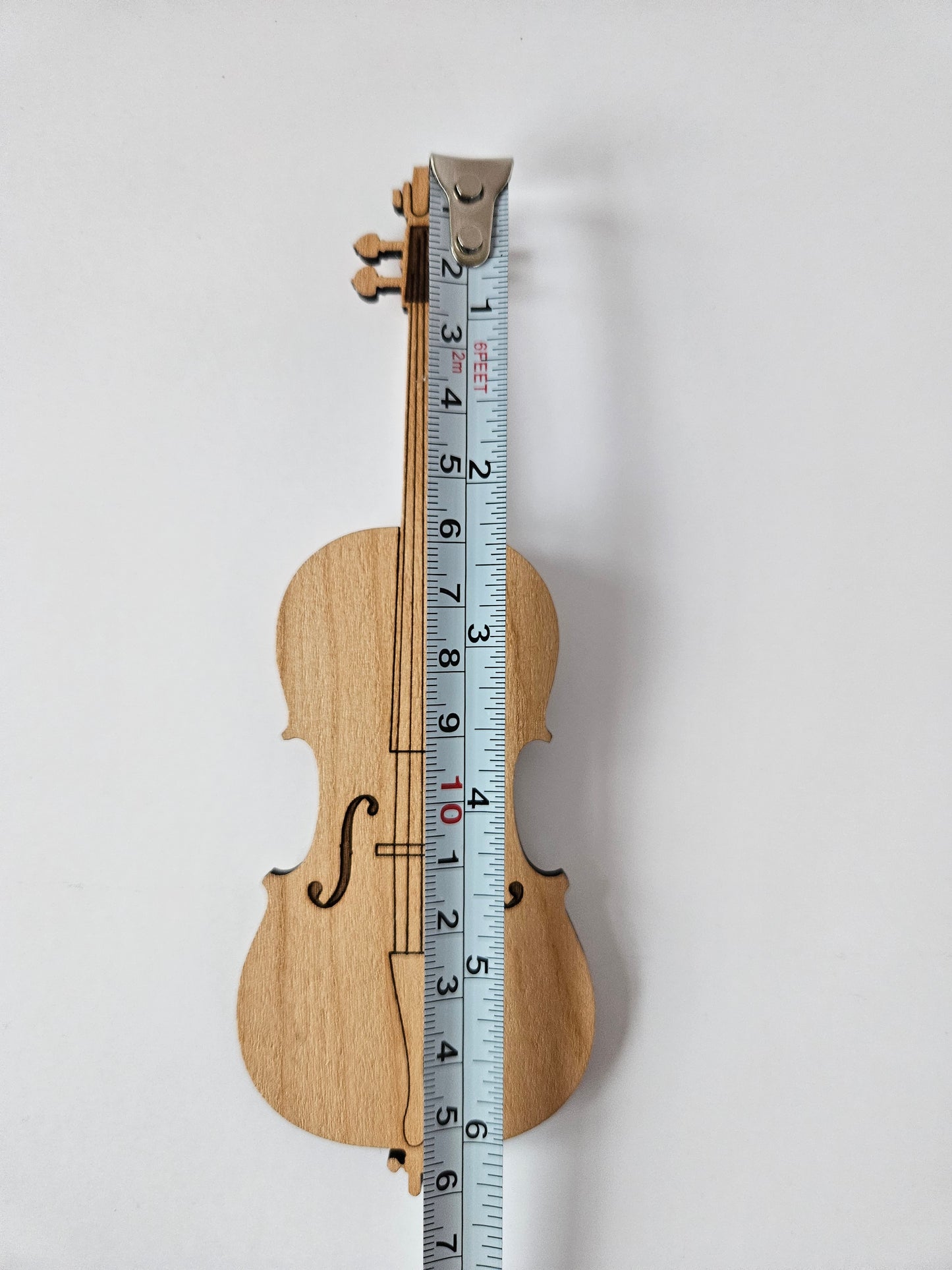 Wooden mini cello with a ruler for scale on a white background. It is about 160 mm or 6 1/2" long.