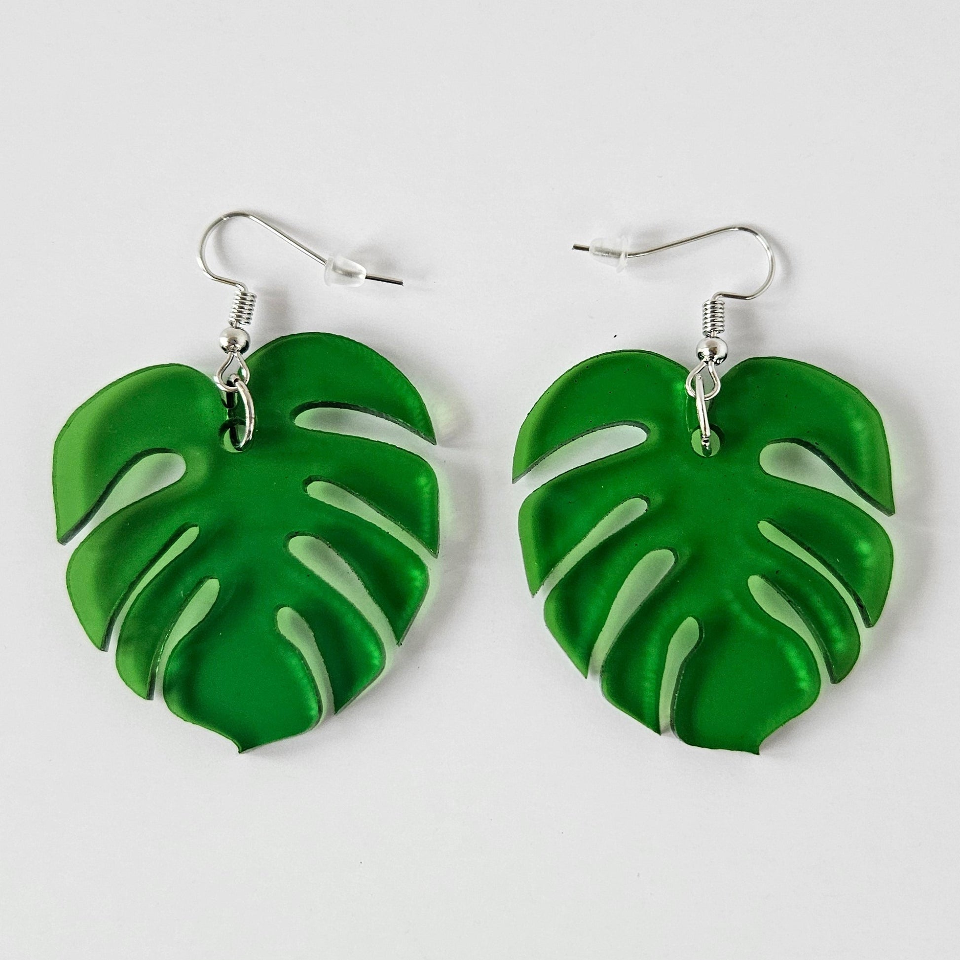 Green Monstera leaf-shaped earrings on a white background