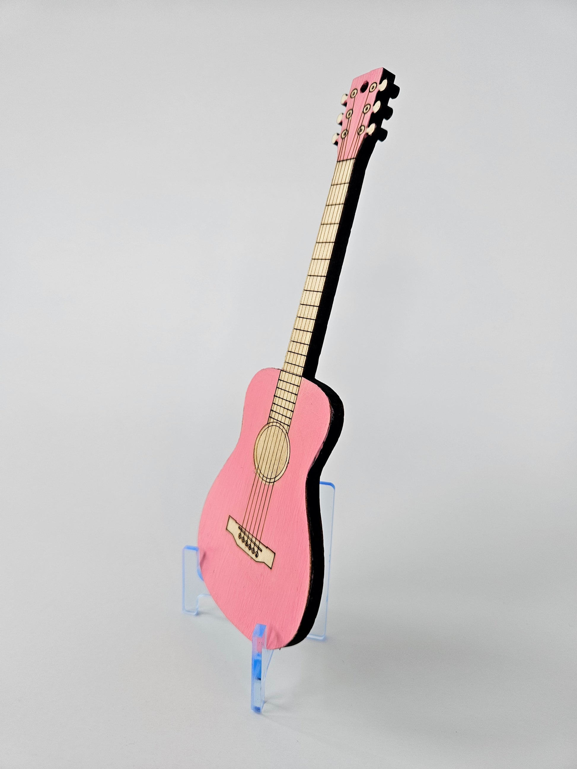 Pink mini acoustic guitar on a gray background - side view
