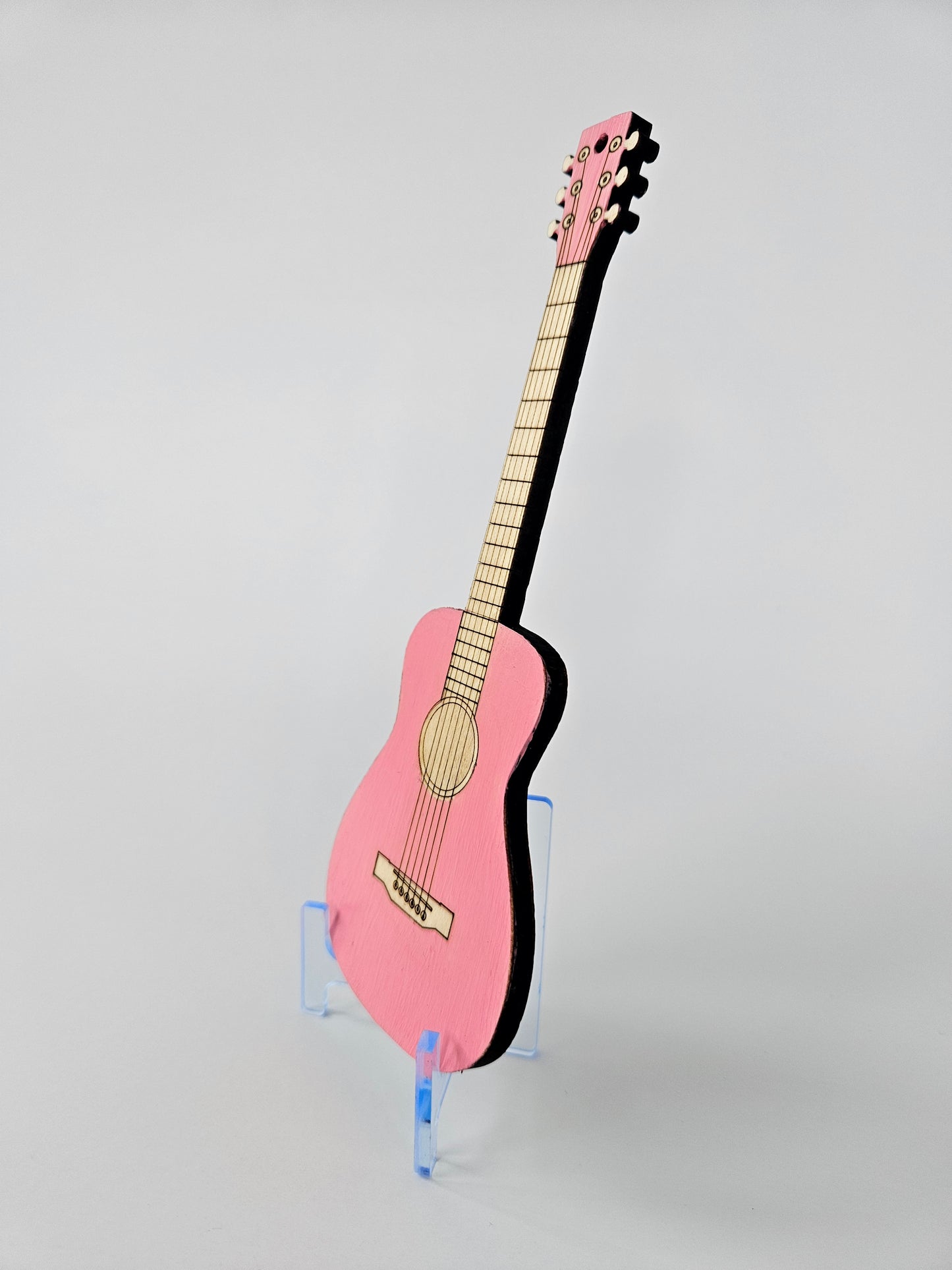 Pink mini acoustic guitar on a gray background - side view
